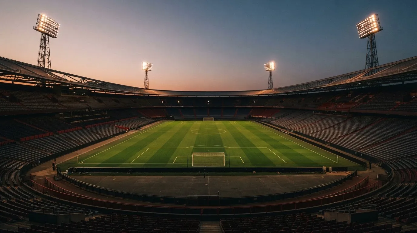 An empty football stadium with floodlight masts at dusk