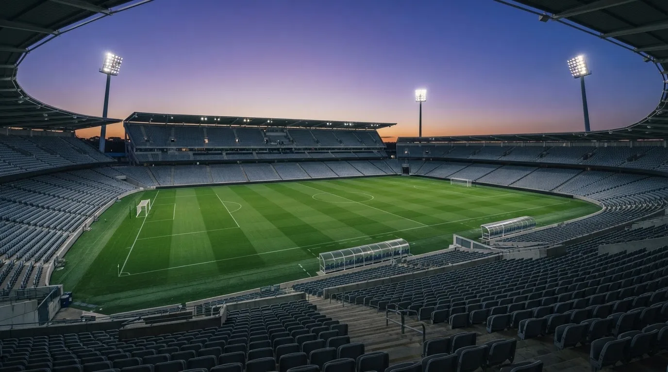 An empty football stadium with floodlight masts at dusk