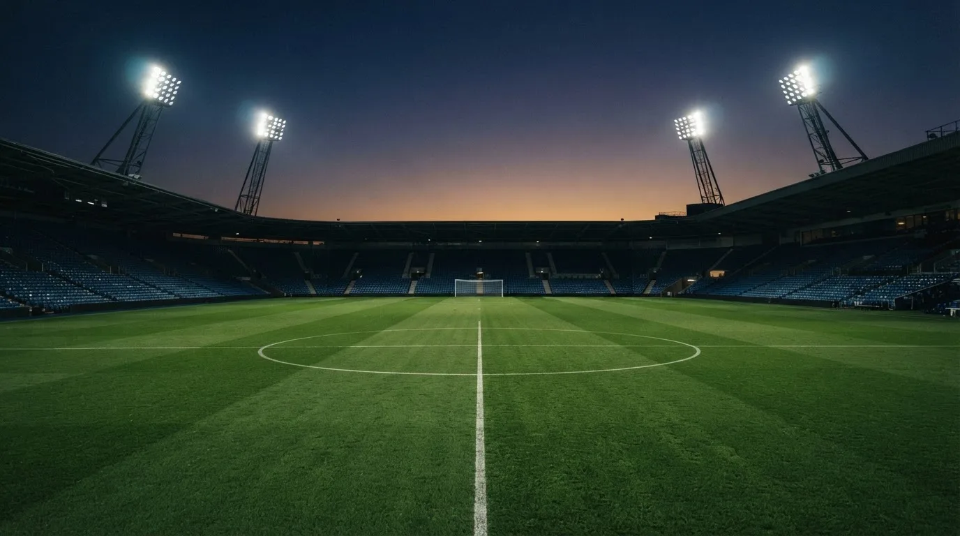 An empty football stadium with floodlight masts at dusk