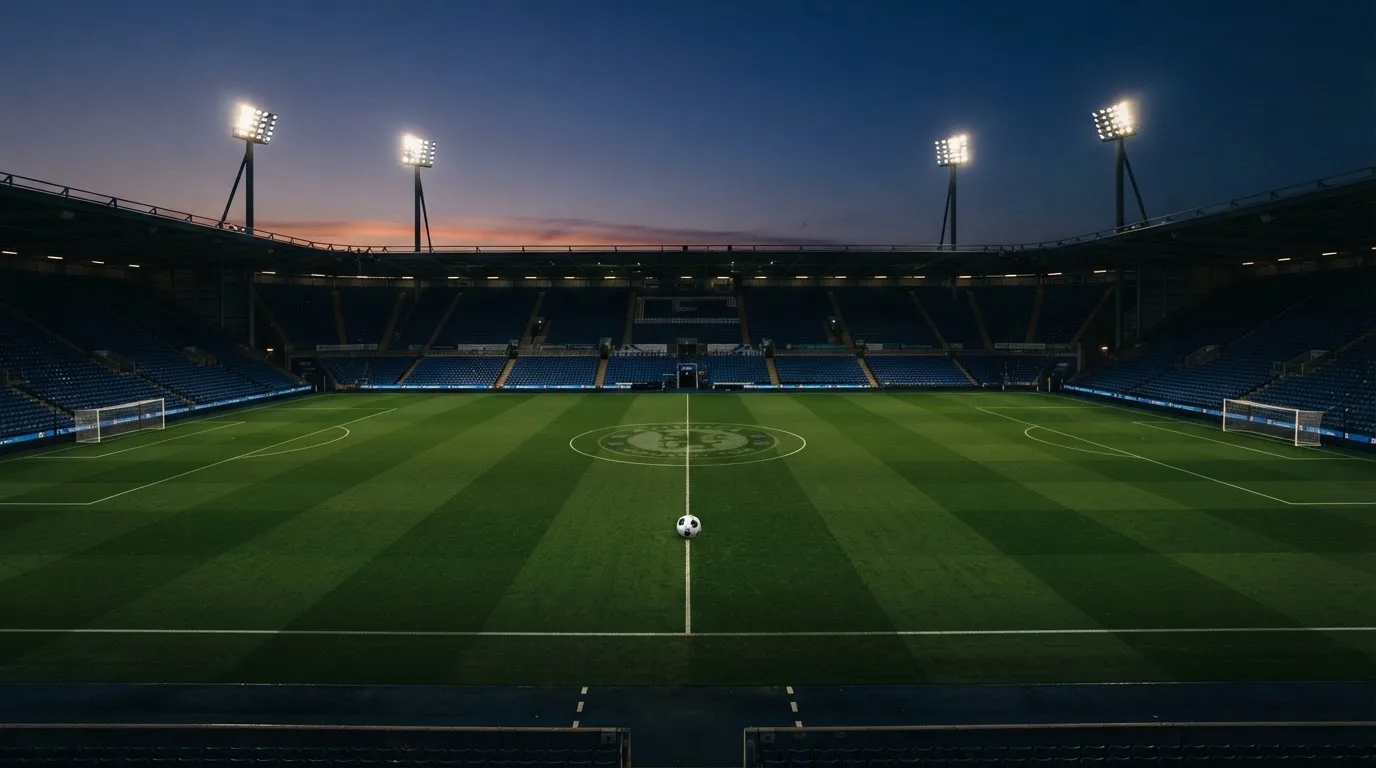 An empty football stadium with floodlight masts at dusk