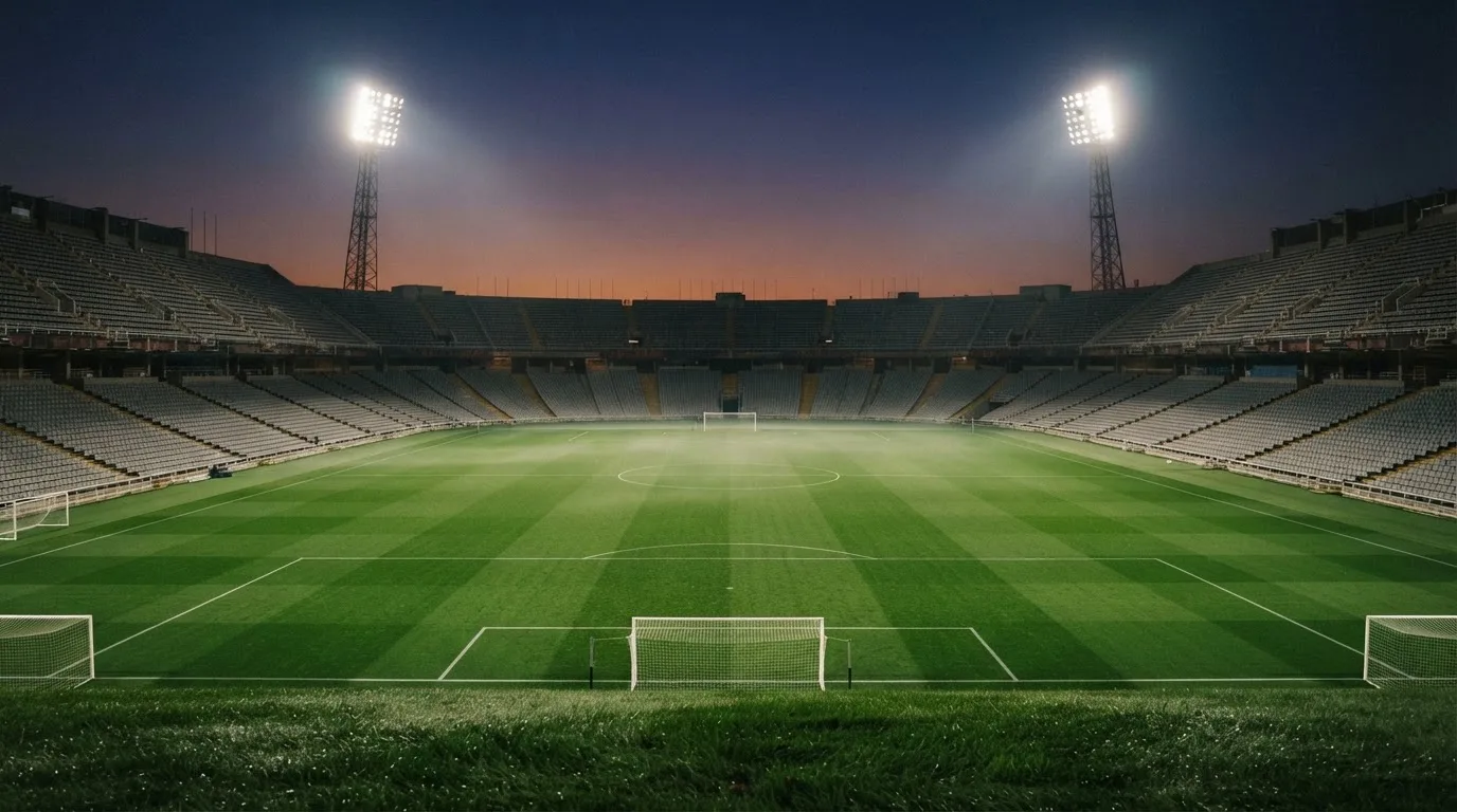 An empty football stadium with floodlight masts at dusk