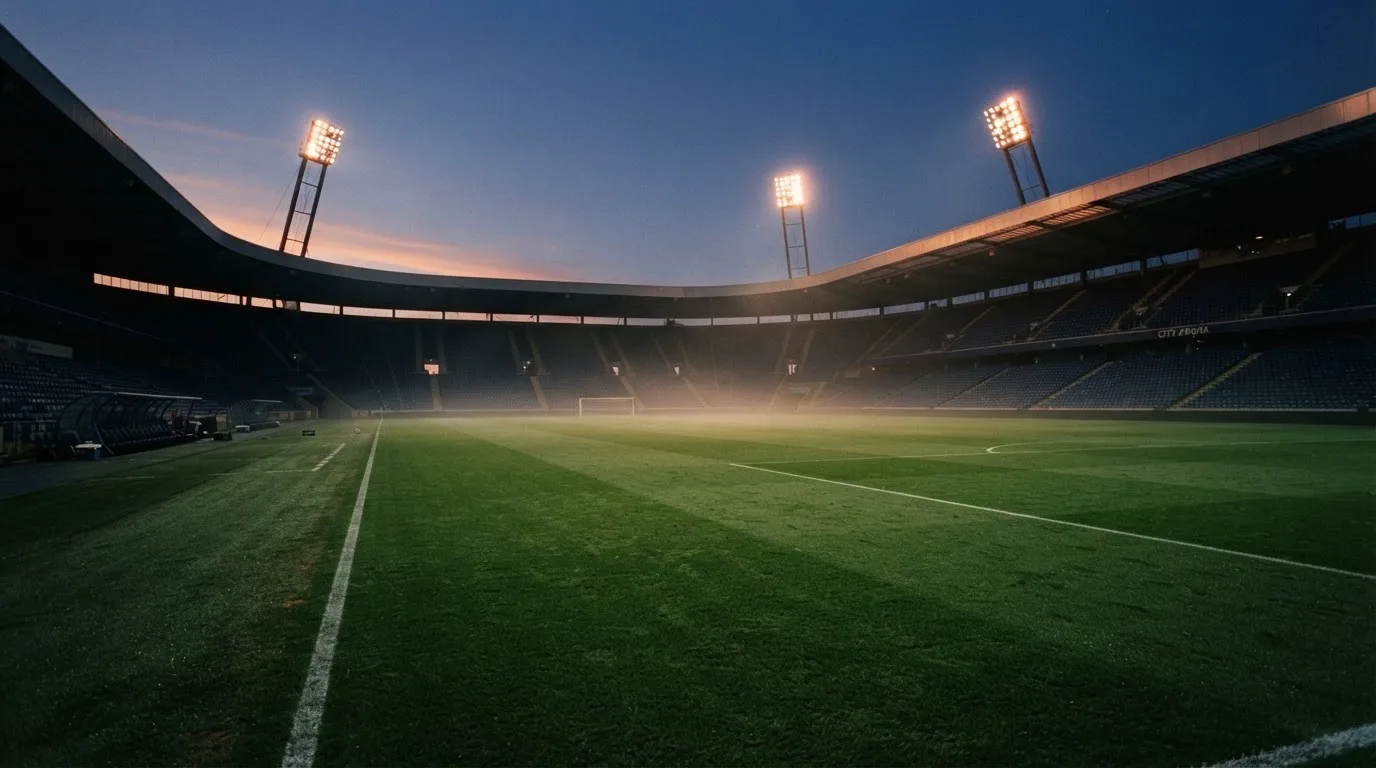 An empty football stadium with floodlight masts at dusk
