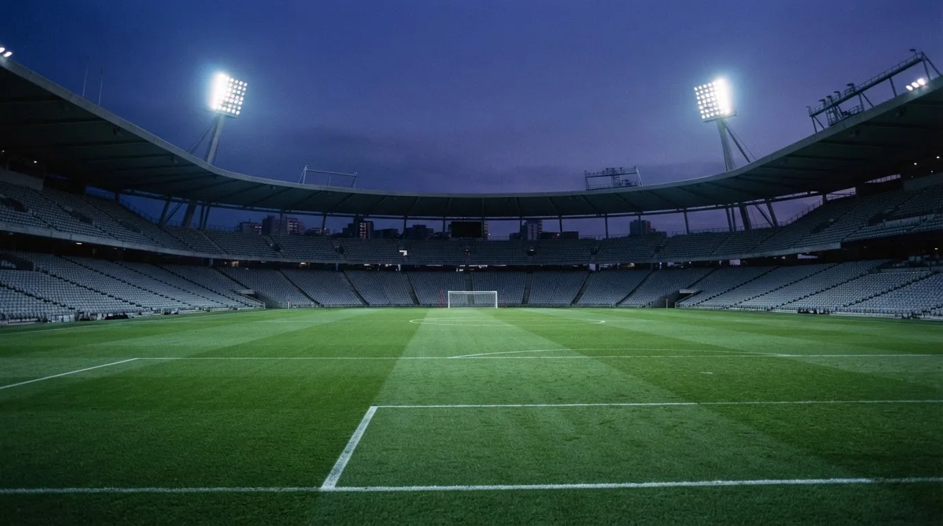 An empty football stadium with floodlight masts at dusk