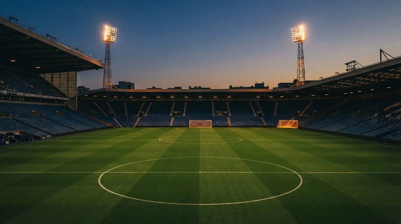 An empty football stadium with floodlight masts at dusk