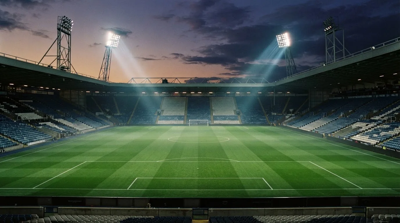An empty football stadium with floodlight masts at dusk