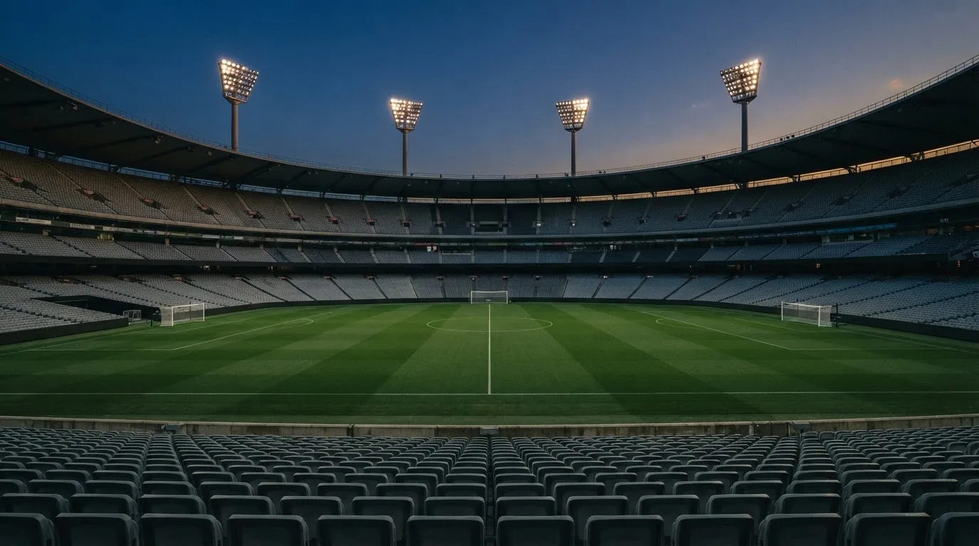 An empty football stadium with floodlight masts at dusk