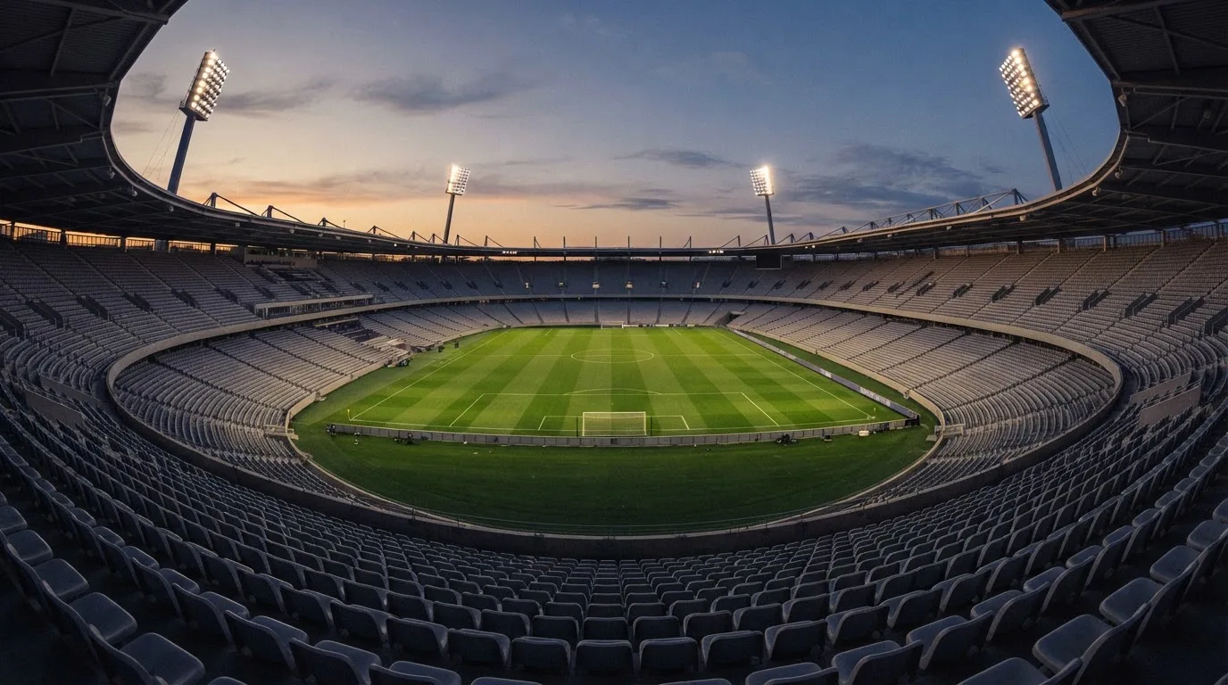 An empty football stadium with floodlight masts at dusk