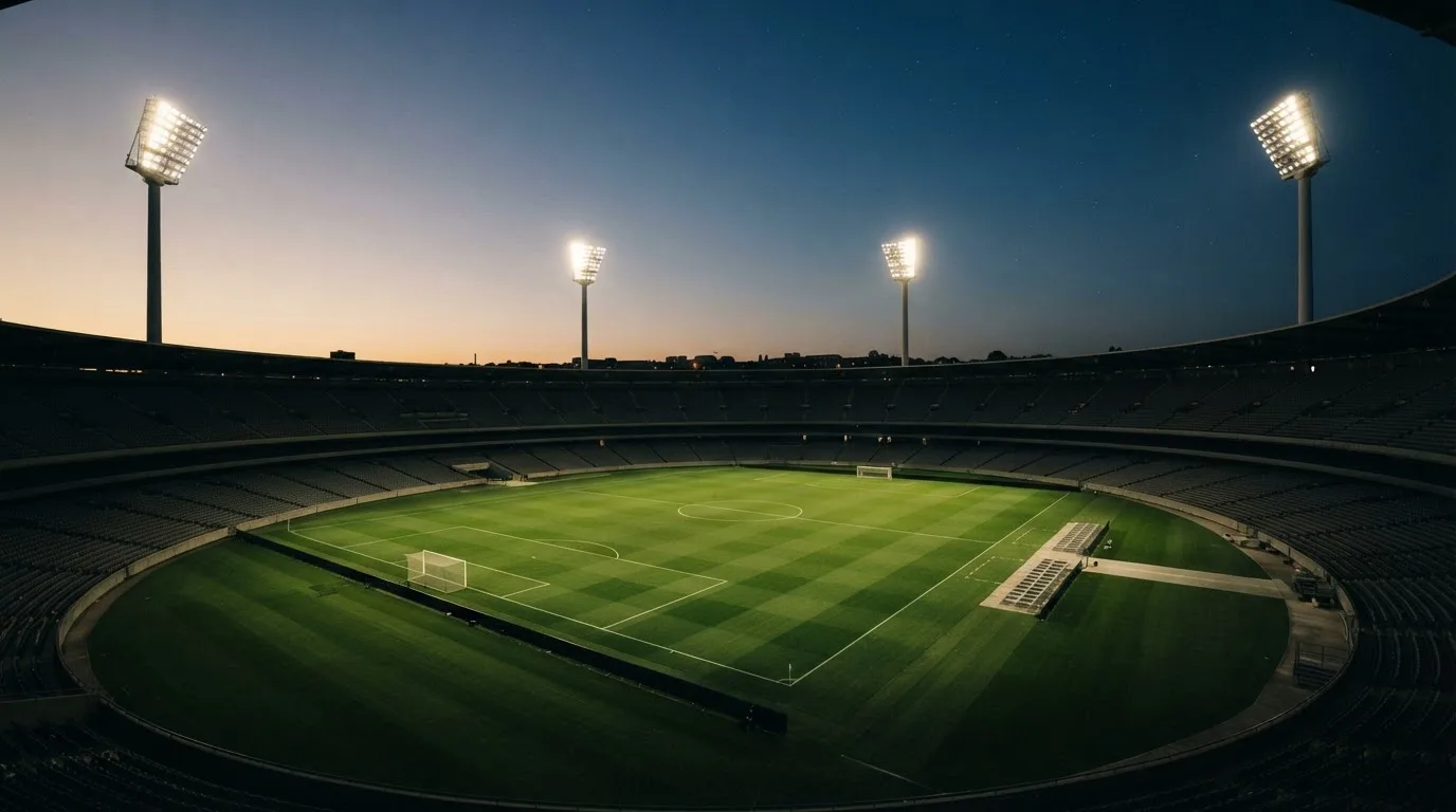 An empty football stadium with floodlight masts at dusk