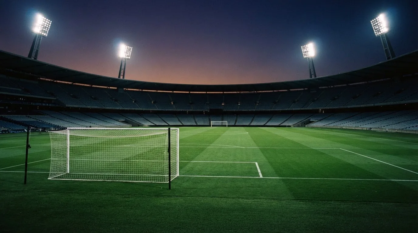 An empty football stadium with floodlight masts at dusk