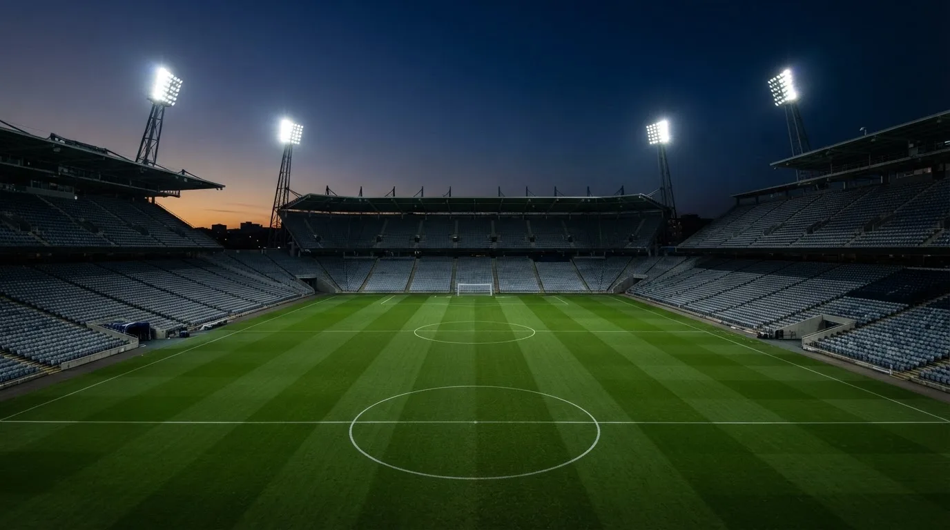 An empty football stadium with floodlight masts at dusk
