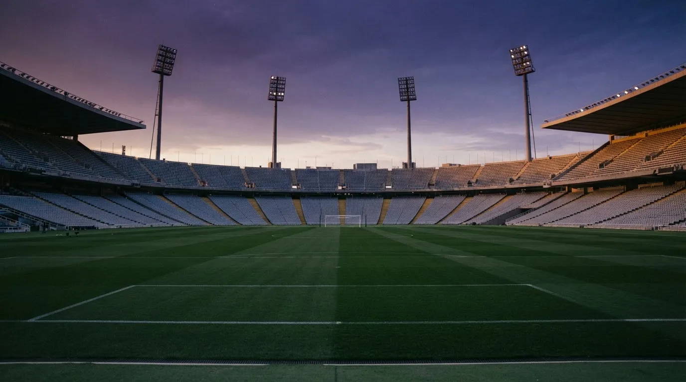 An empty football stadium with floodlight masts at dusk