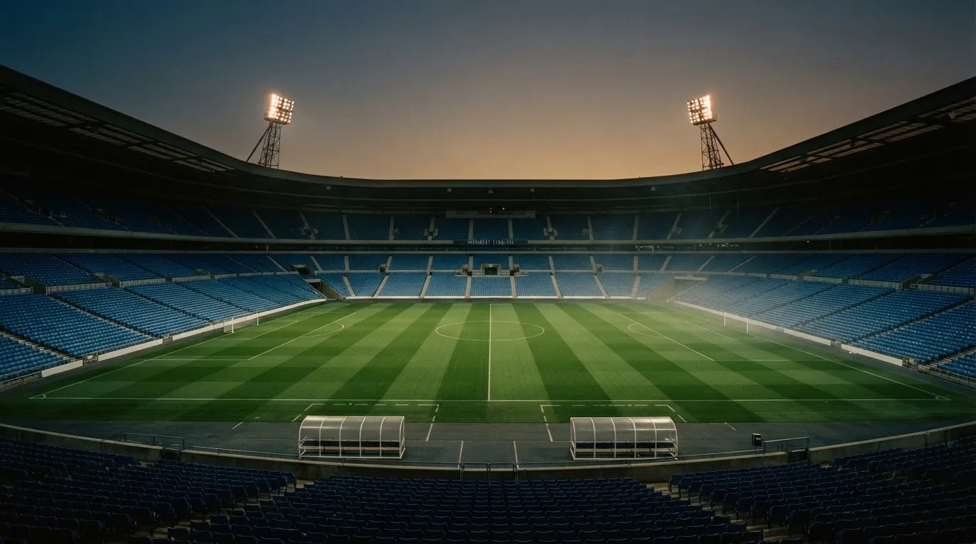 An empty football stadium with floodlight masts at dusk