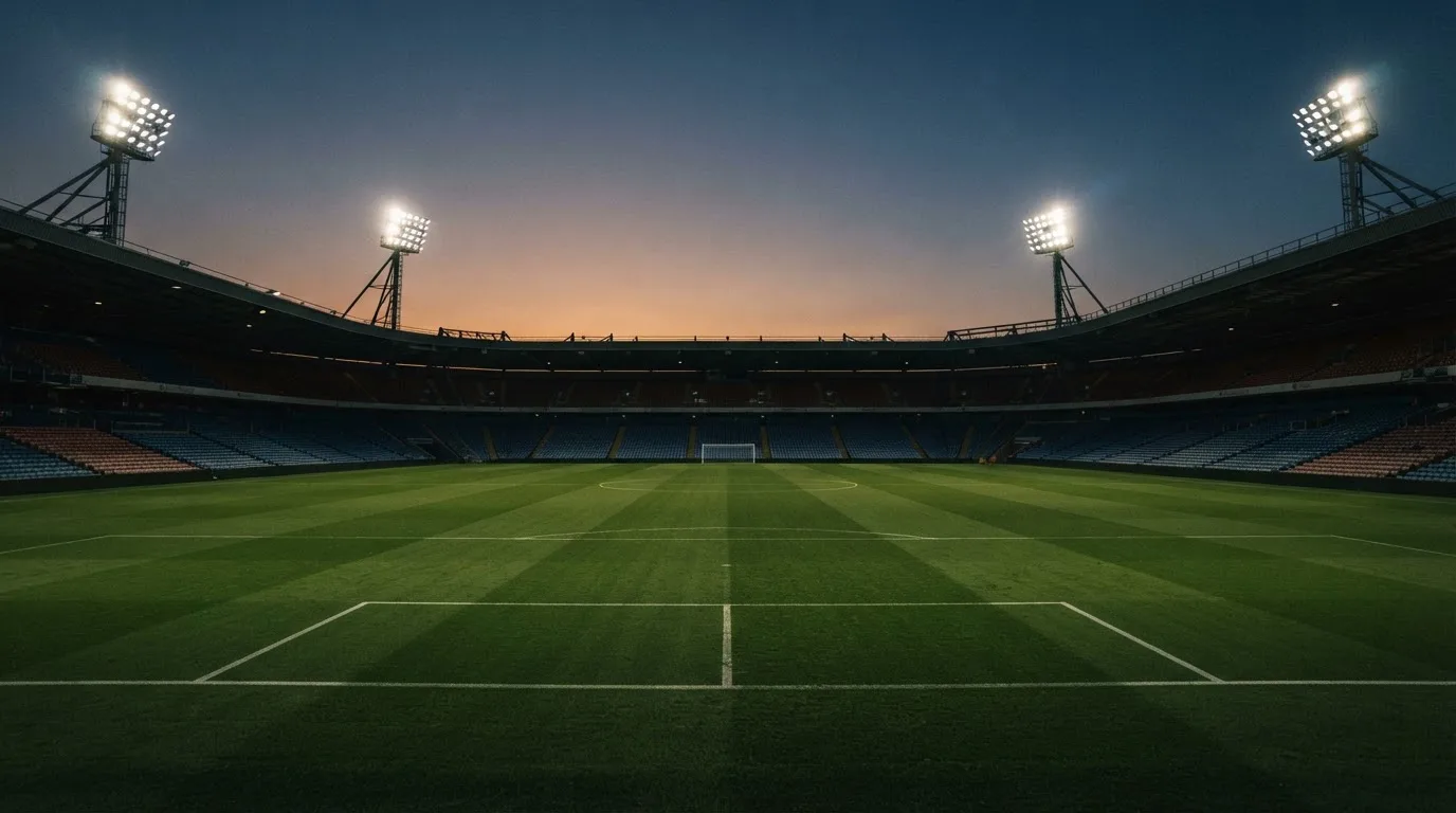 An empty football stadium with floodlight masts at dusk