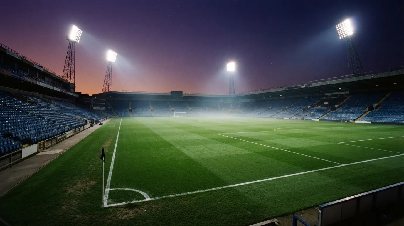 An empty football stadium with floodlight masts at dusk