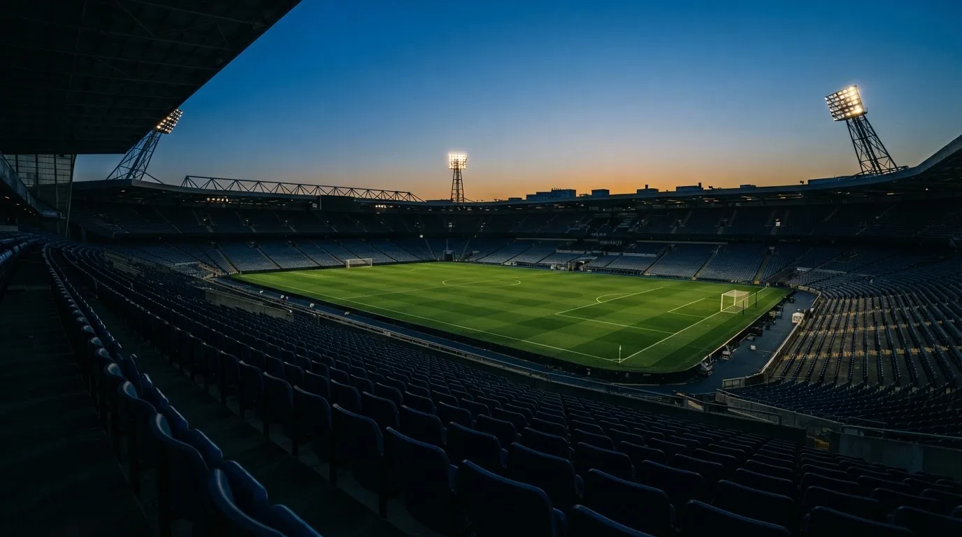 An empty football stadium with floodlight masts at dusk