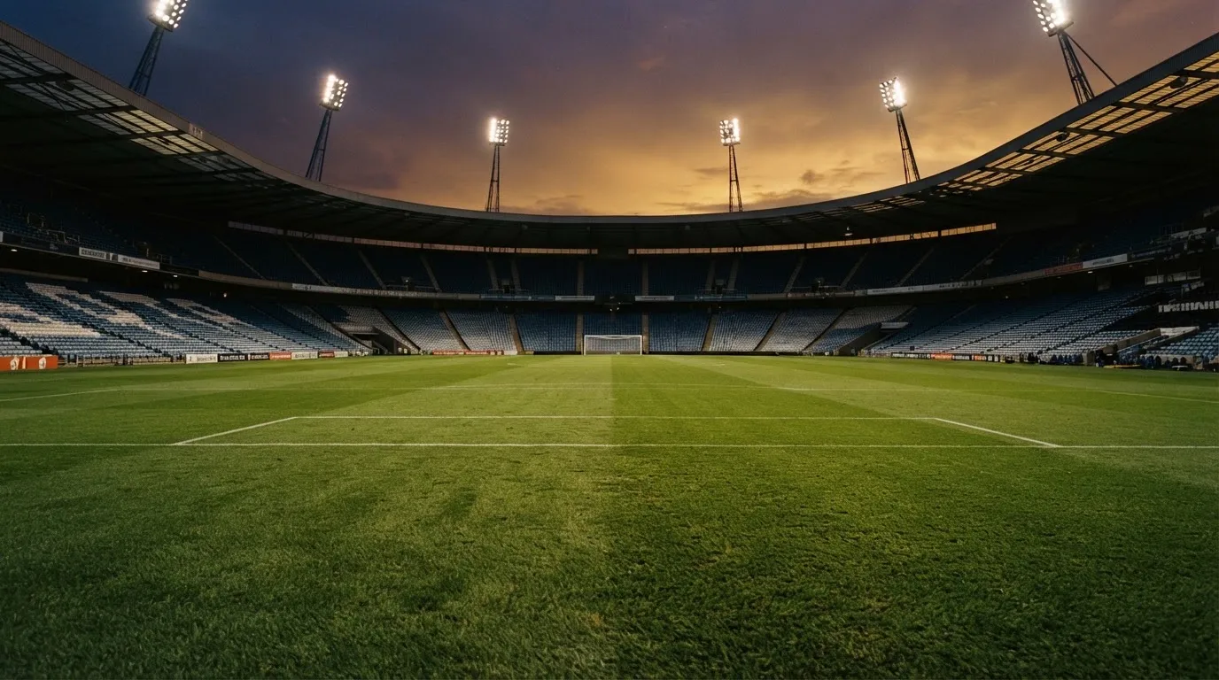 An empty football stadium with floodlight masts at dusk