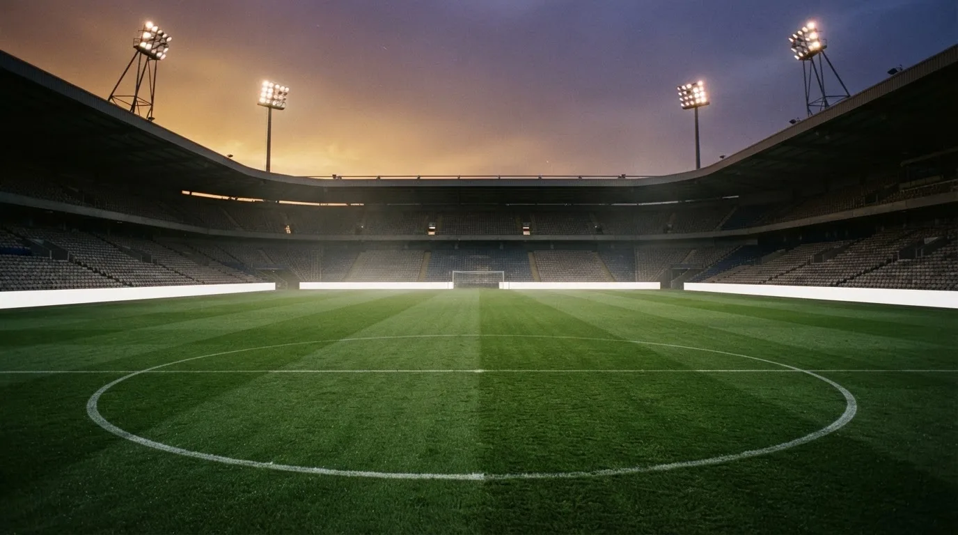 An empty football stadium with floodlight masts at dusk