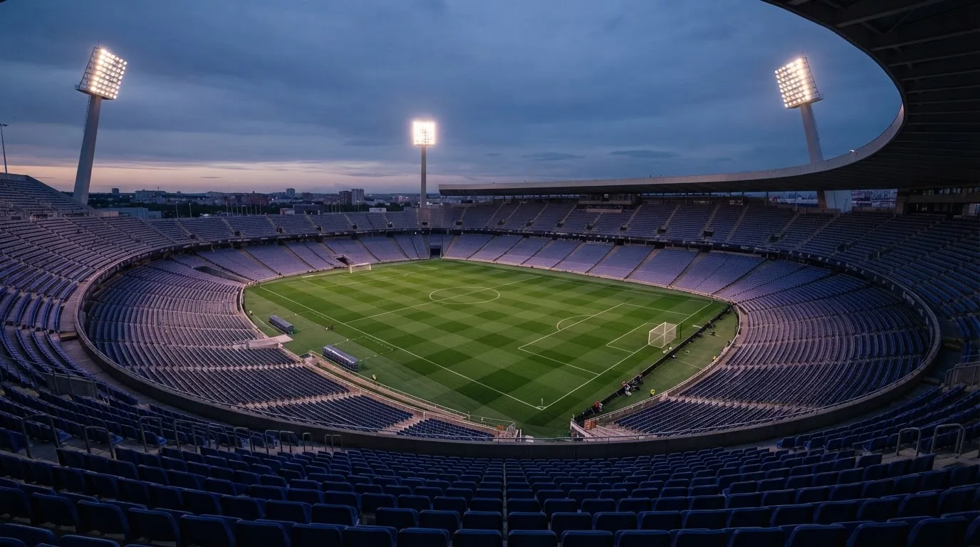 An empty football stadium with floodlight masts at dusk