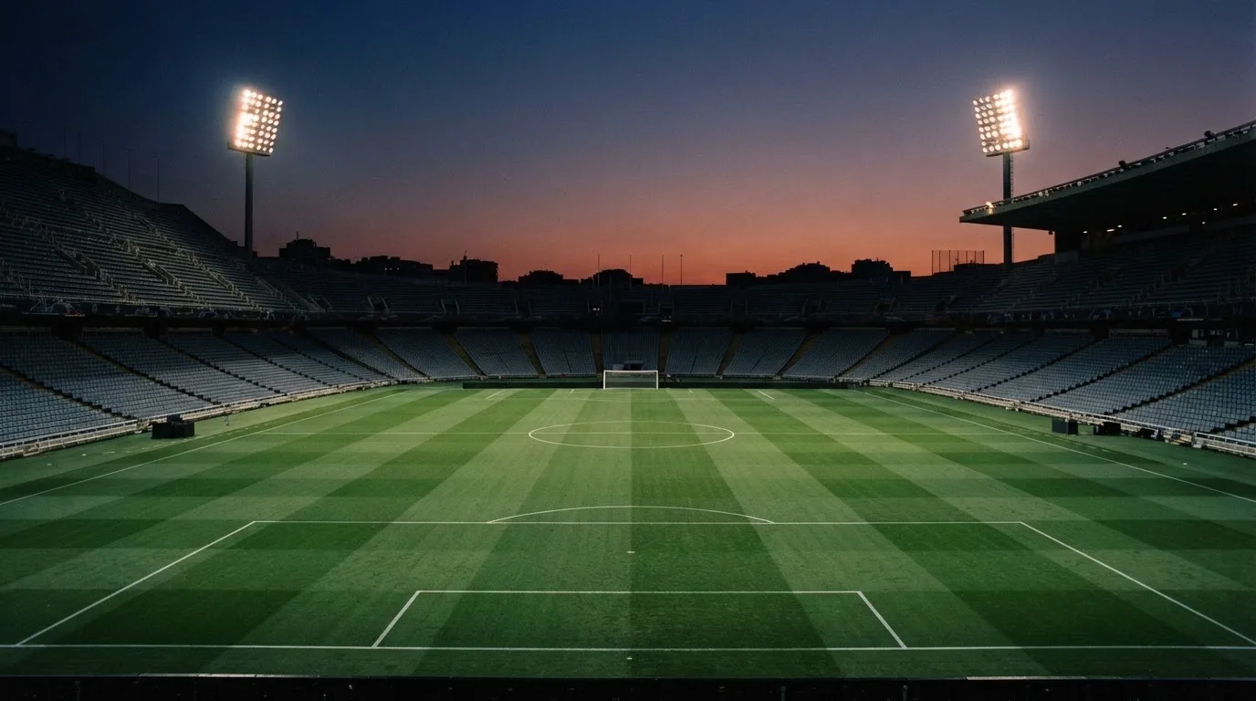 An empty football stadium with floodlight masts at dusk