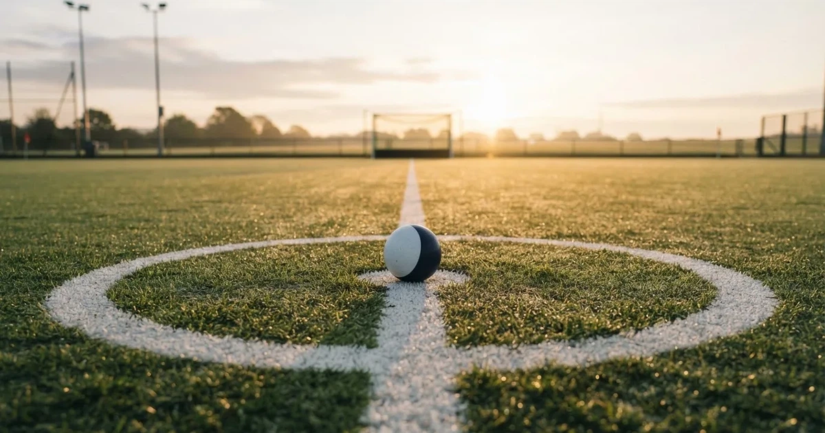 A ball on the centre spot of a grass pitch in morning light