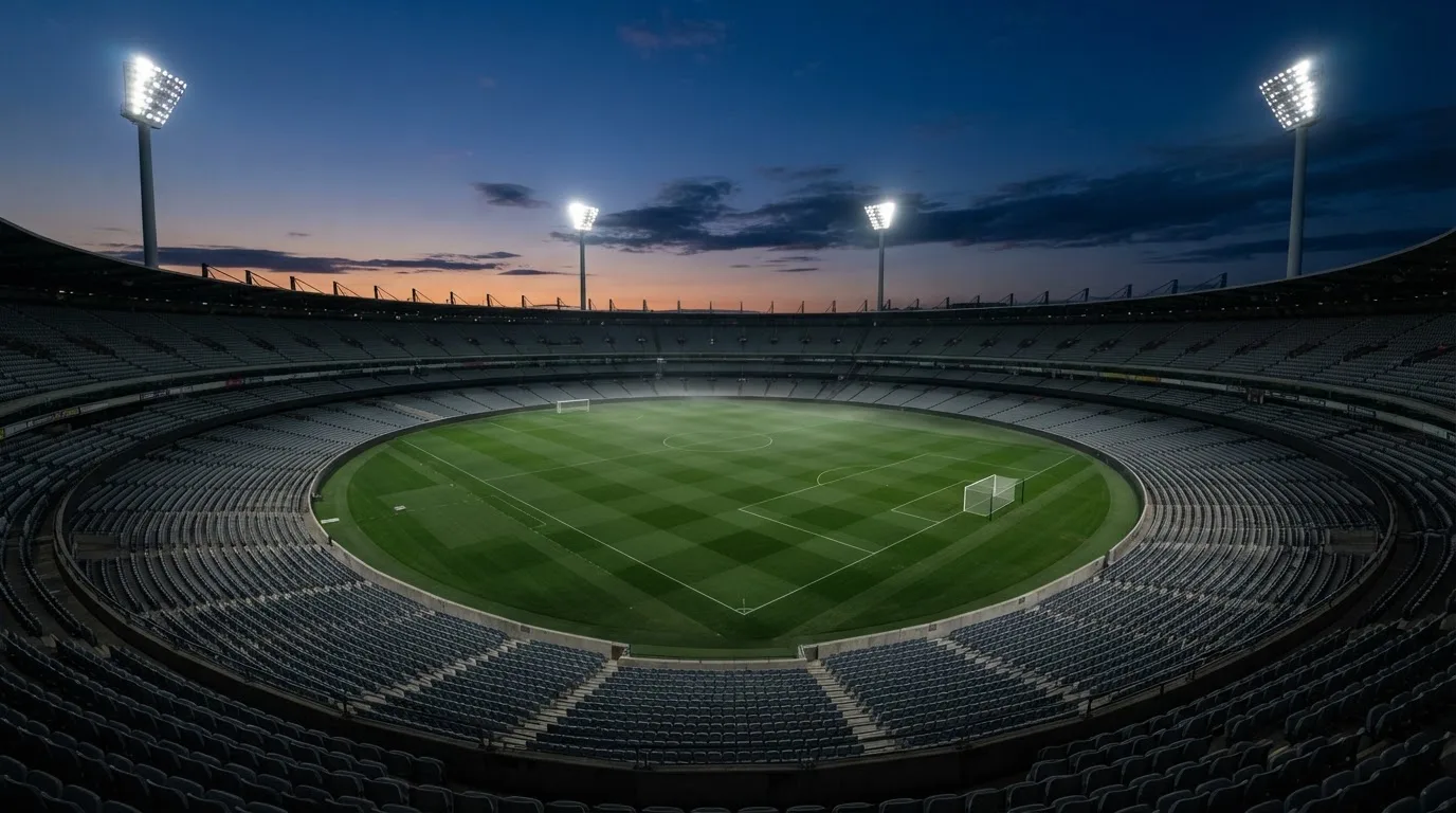 An empty football stadium with floodlight masts at dusk