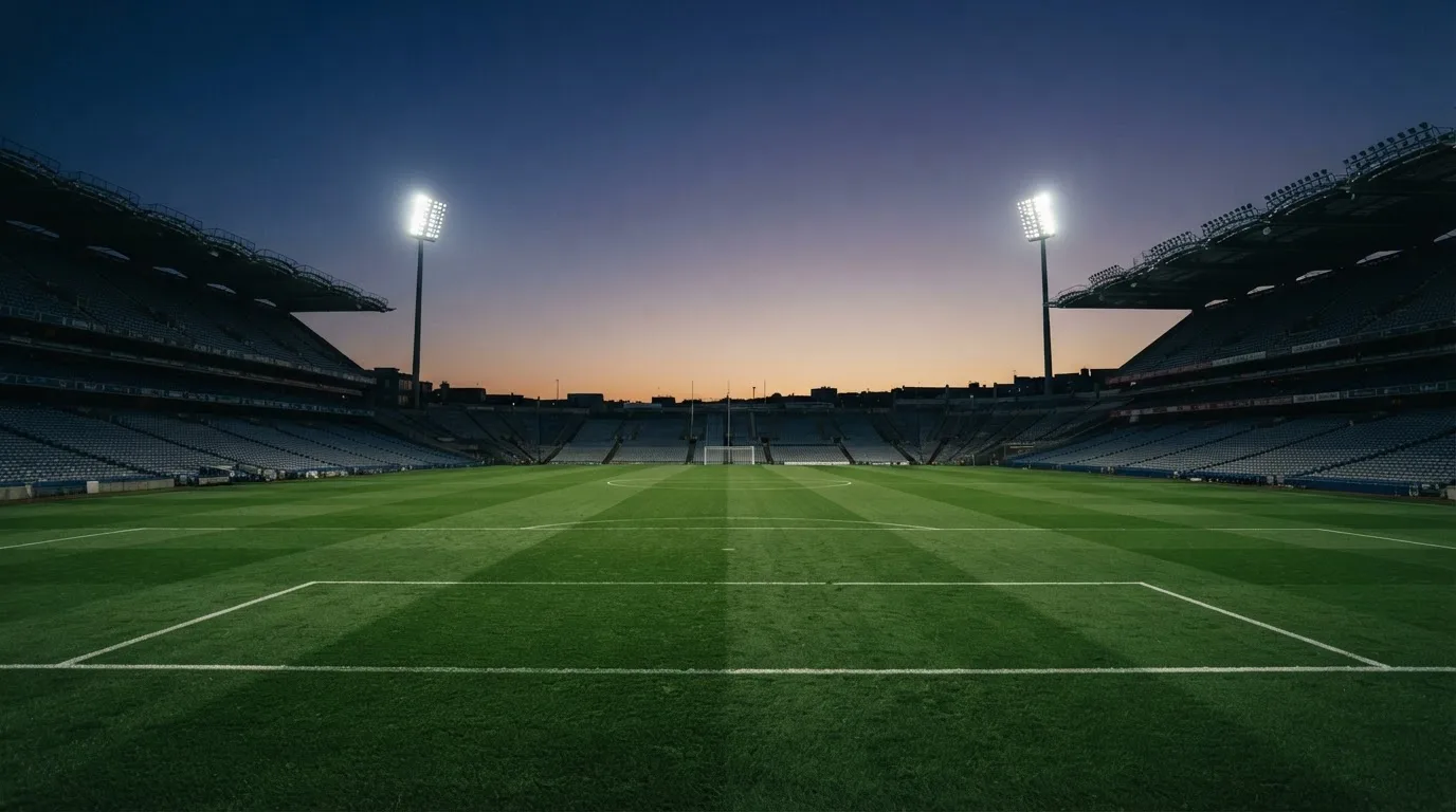 An empty football stadium with floodlight masts at dusk