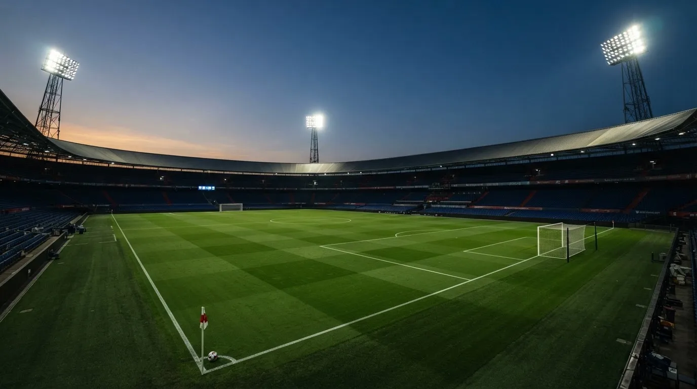 An empty football stadium with floodlight masts at dusk