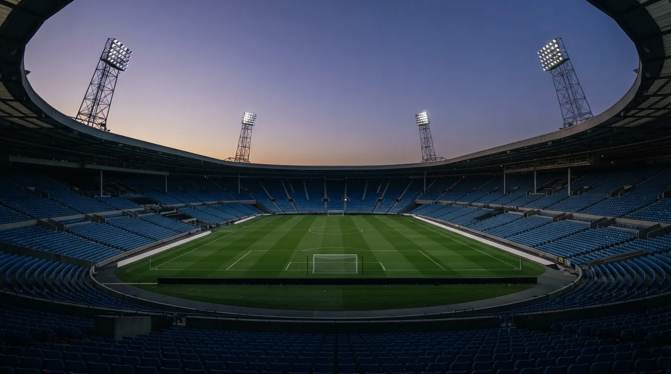 An empty football stadium with floodlight masts at dusk