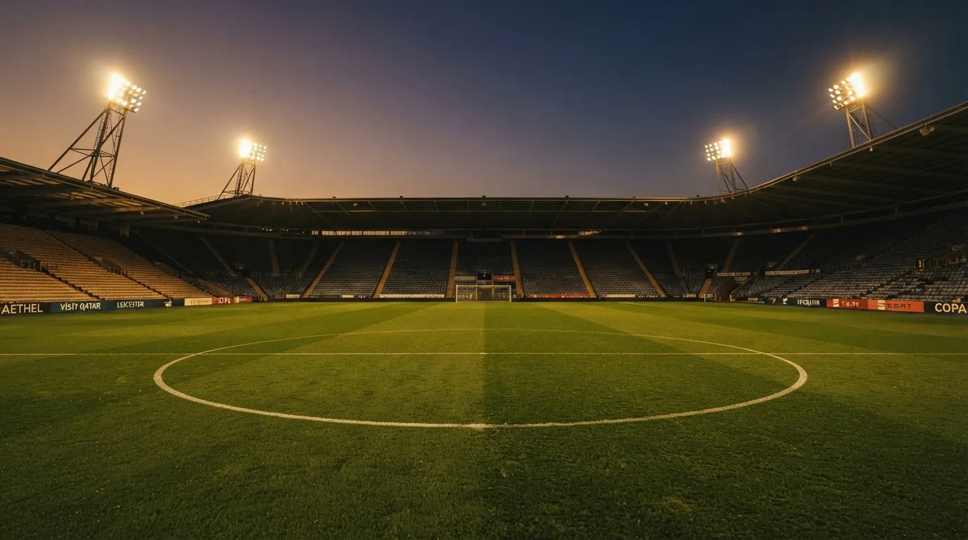 An empty football stadium with floodlight masts at dusk