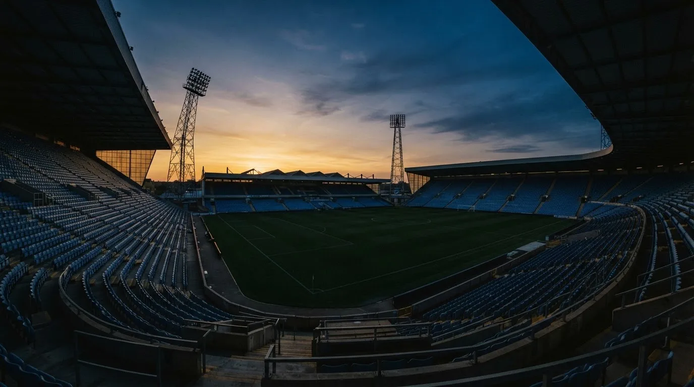 An empty football stadium with floodlight masts at dusk