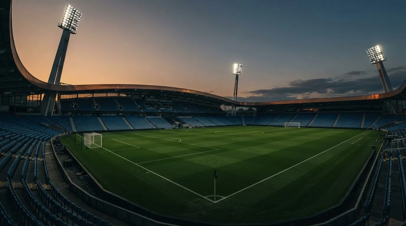 An empty football stadium with floodlight masts at dusk