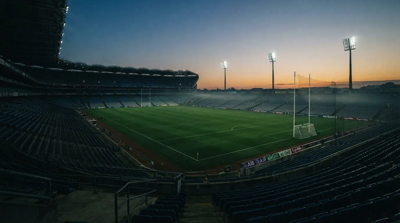 An empty football stadium with floodlight masts at dusk