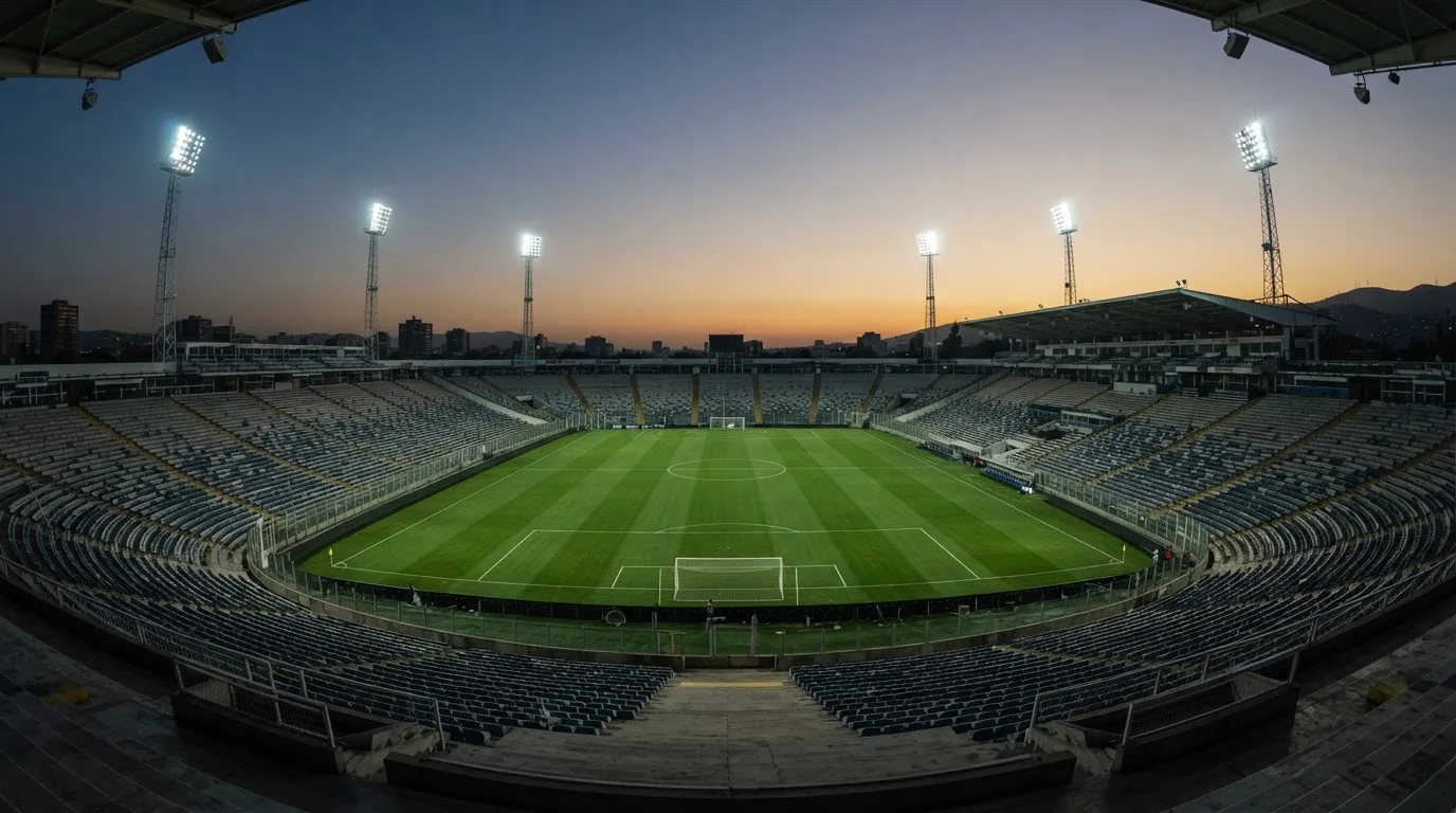 An empty football stadium with floodlight masts at dusk