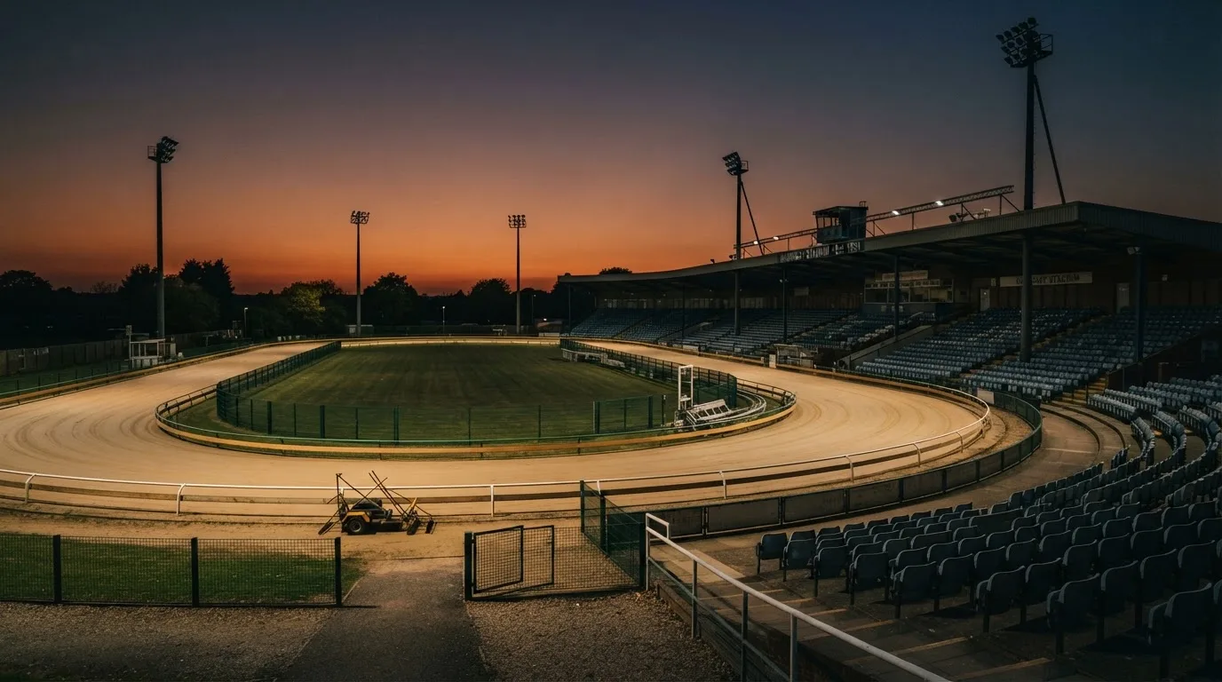 An empty football stadium with floodlight masts at dusk