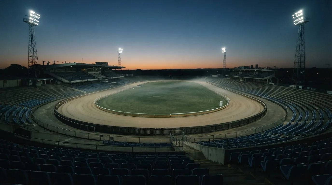 An empty football stadium with floodlight masts at dusk