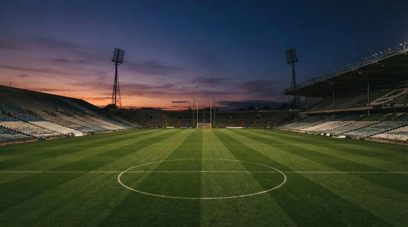 An empty football stadium with floodlight masts at dusk