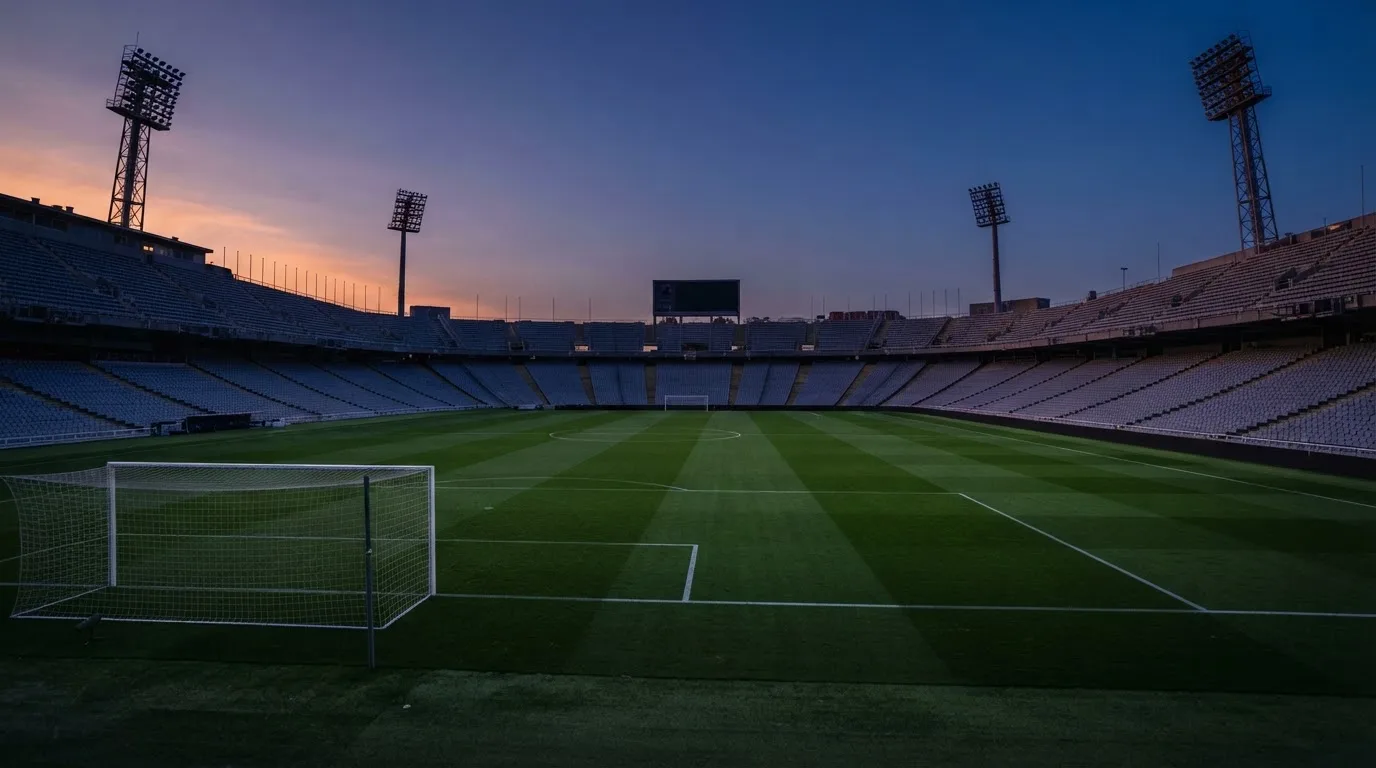 An empty football stadium with floodlight masts at dusk