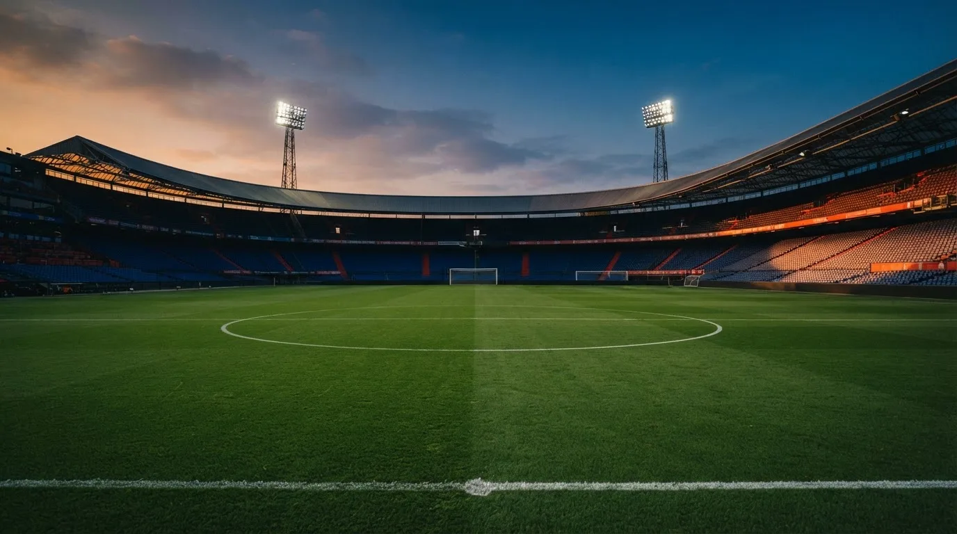 An empty football stadium with floodlight masts at dusk
