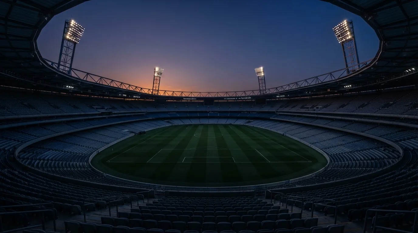 An empty football stadium with floodlight masts at dusk