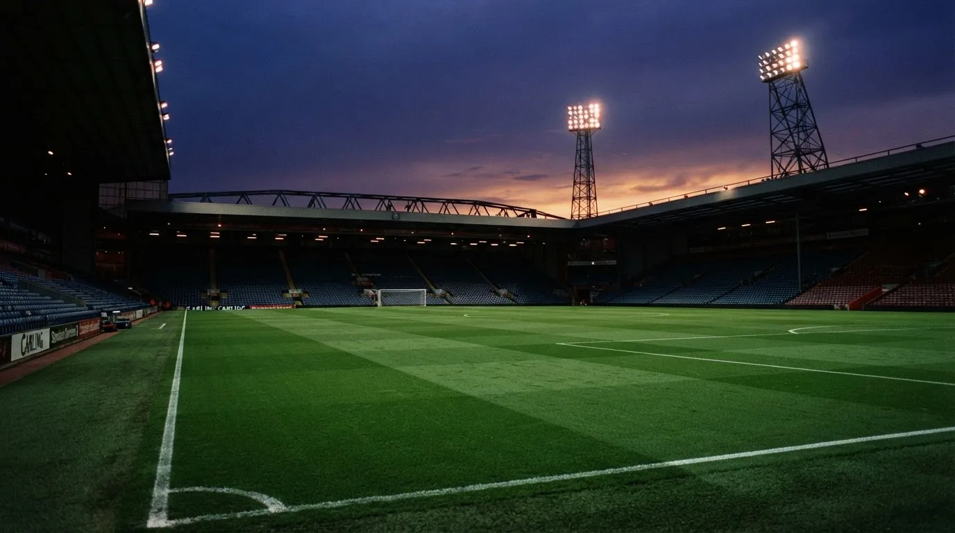 An empty football stadium with floodlight masts at dusk