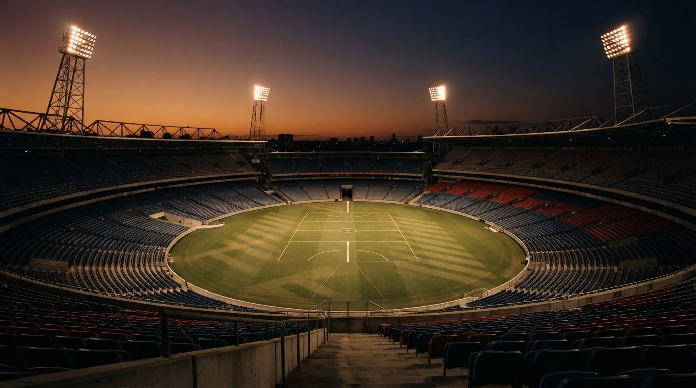 An empty football stadium with floodlight masts at dusk