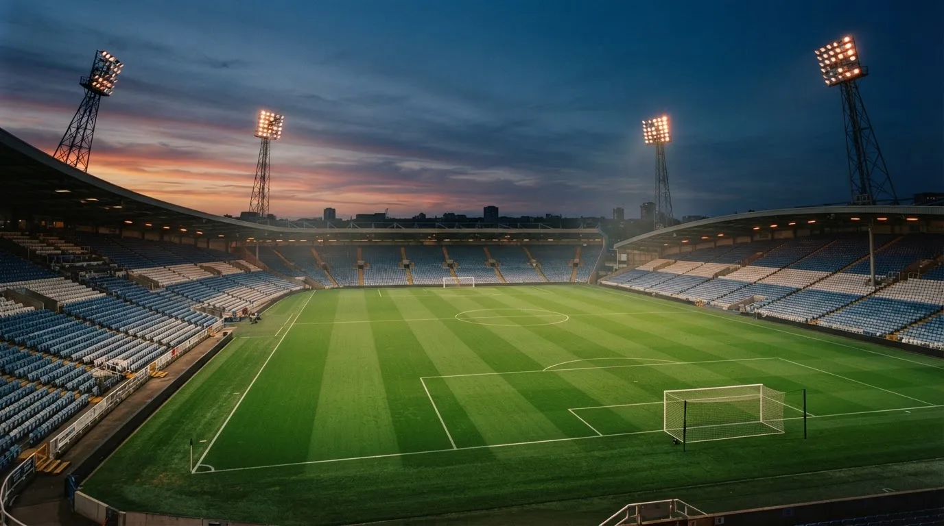 An empty football stadium with floodlight masts at dusk