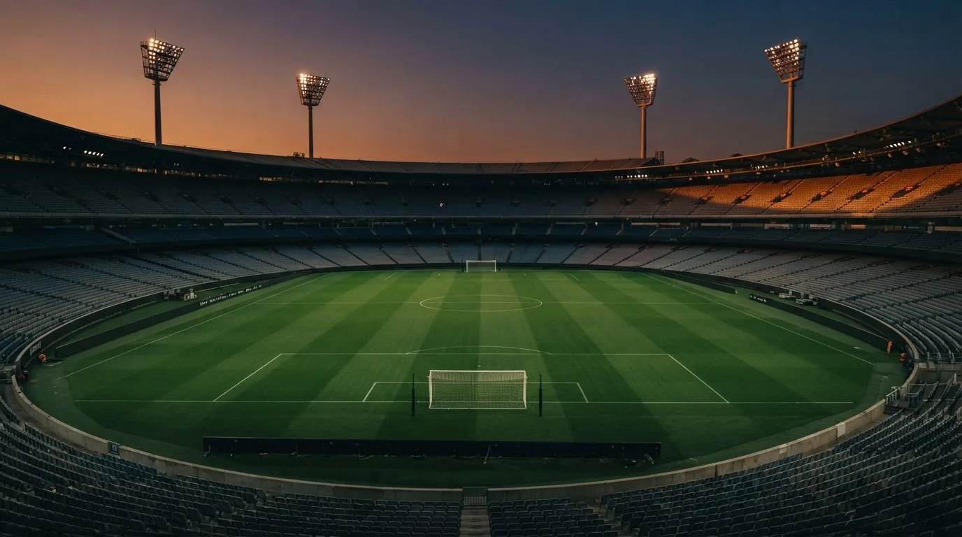 An empty football stadium with floodlight masts at dusk