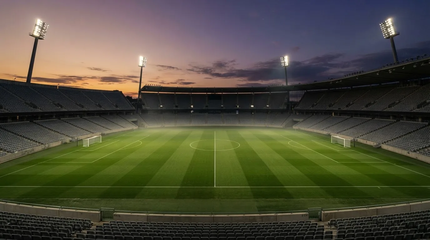 An empty football stadium with floodlight masts at dusk