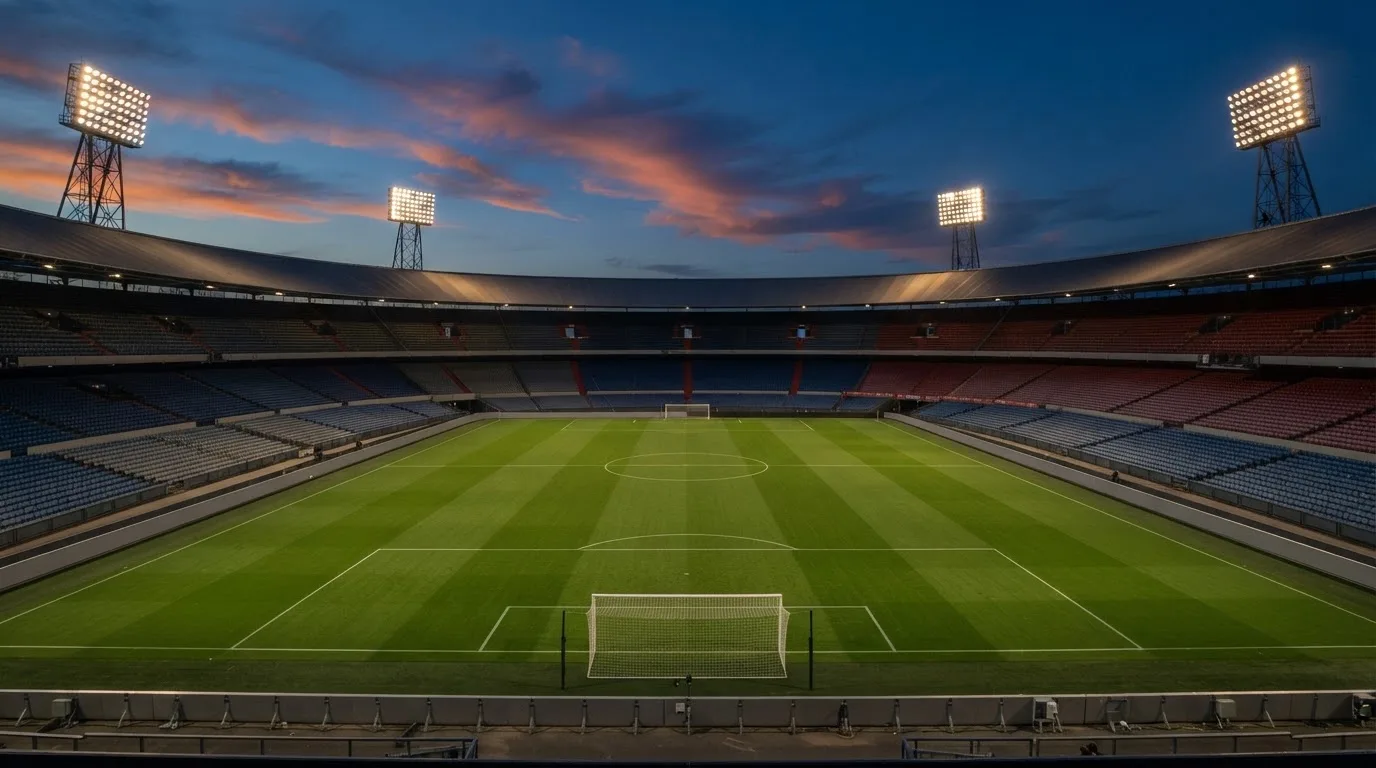 An empty football stadium with floodlight masts at dusk