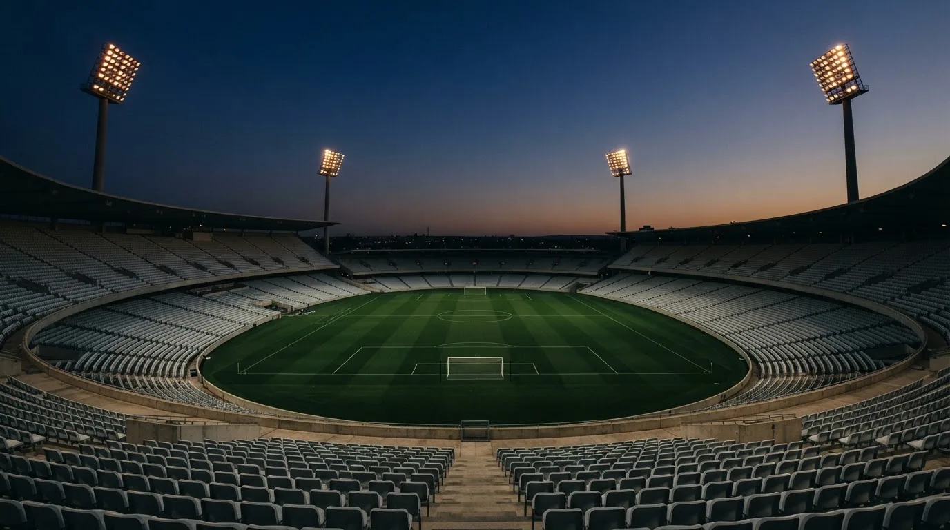 An empty football stadium with floodlight masts at dusk