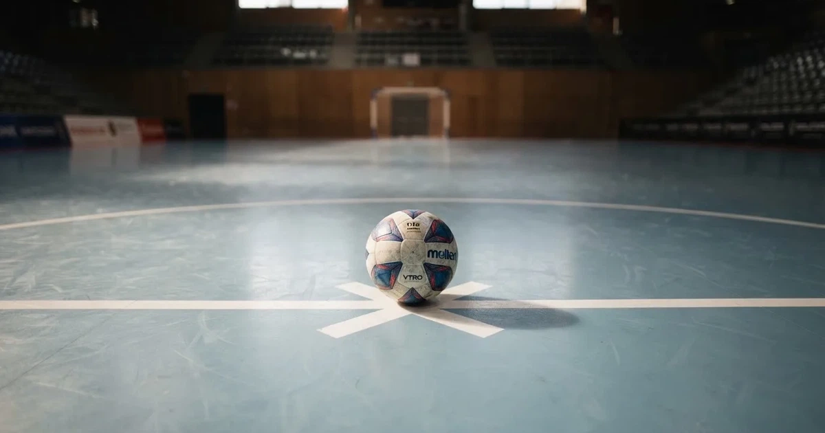 A ball on the centre spot of a grass pitch in morning light