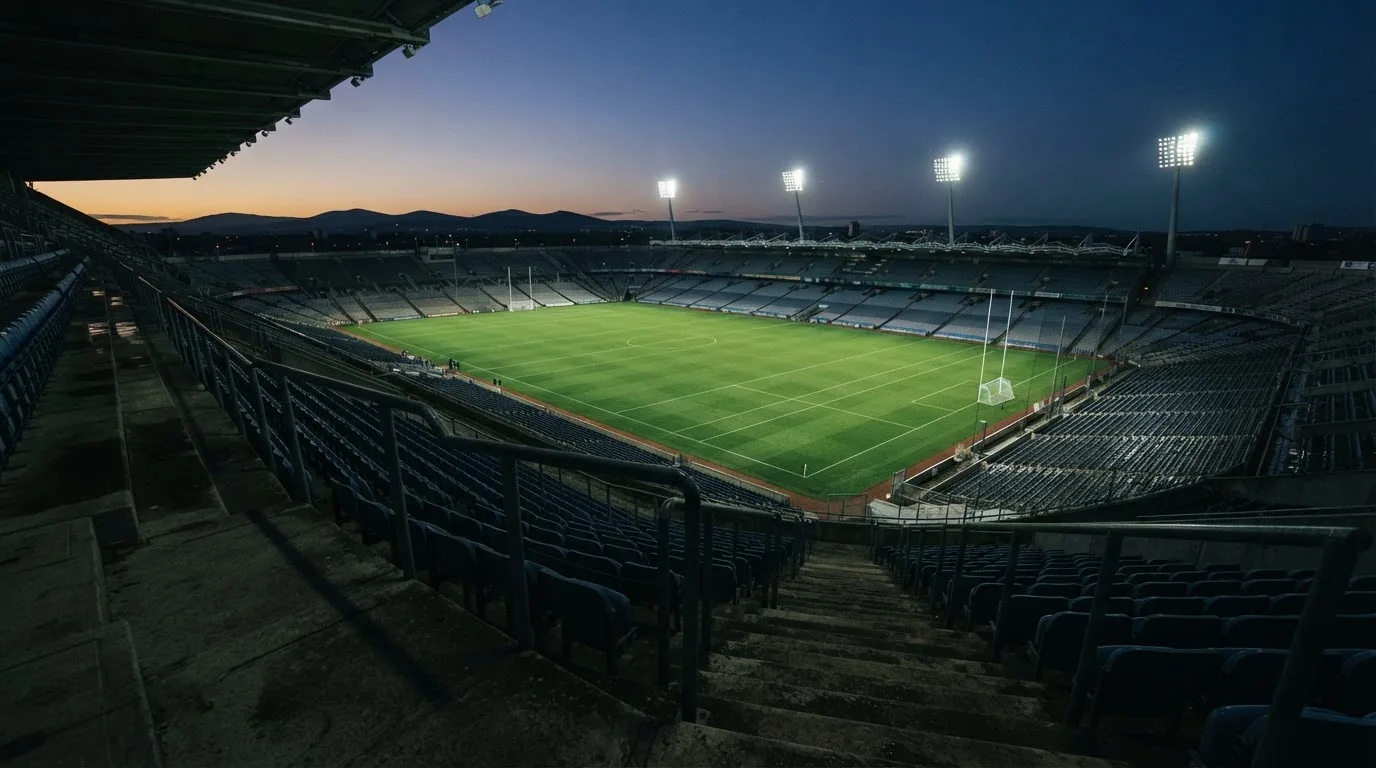 An empty football stadium with floodlight masts at dusk