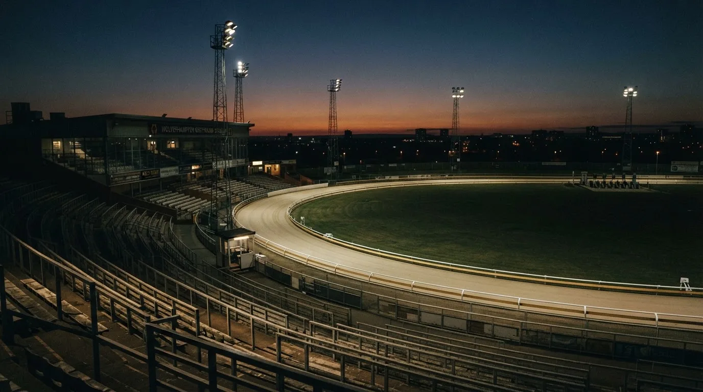 An empty football stadium with floodlight masts at dusk