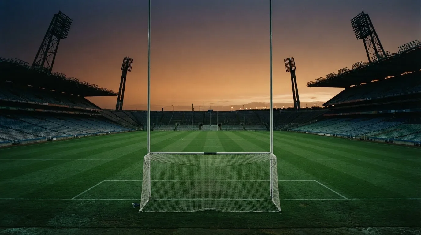An empty football stadium with floodlight masts at dusk